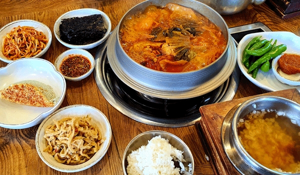 Kimchi jjigae servido con arroz y pequeñas guarniciones coreanas