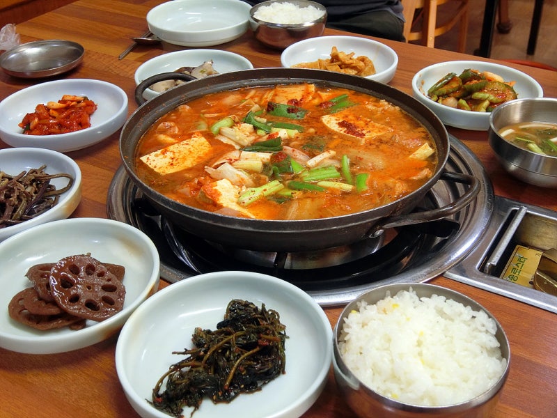 Una mesa de comida casera coreana con kimchi jjigae como plato principal