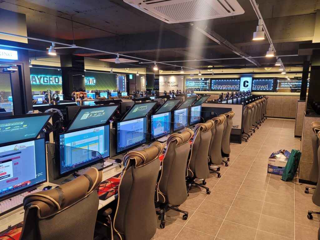 Fileiras de PCs gamer e cadeiras dentro de um PC bang coreano