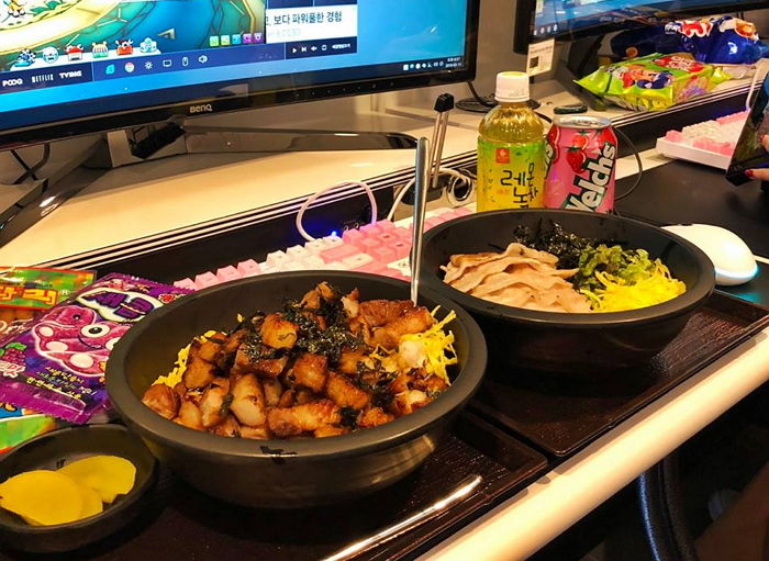 Mesa de PC bang na Coreia com comida e bebidas ao lado do teclado