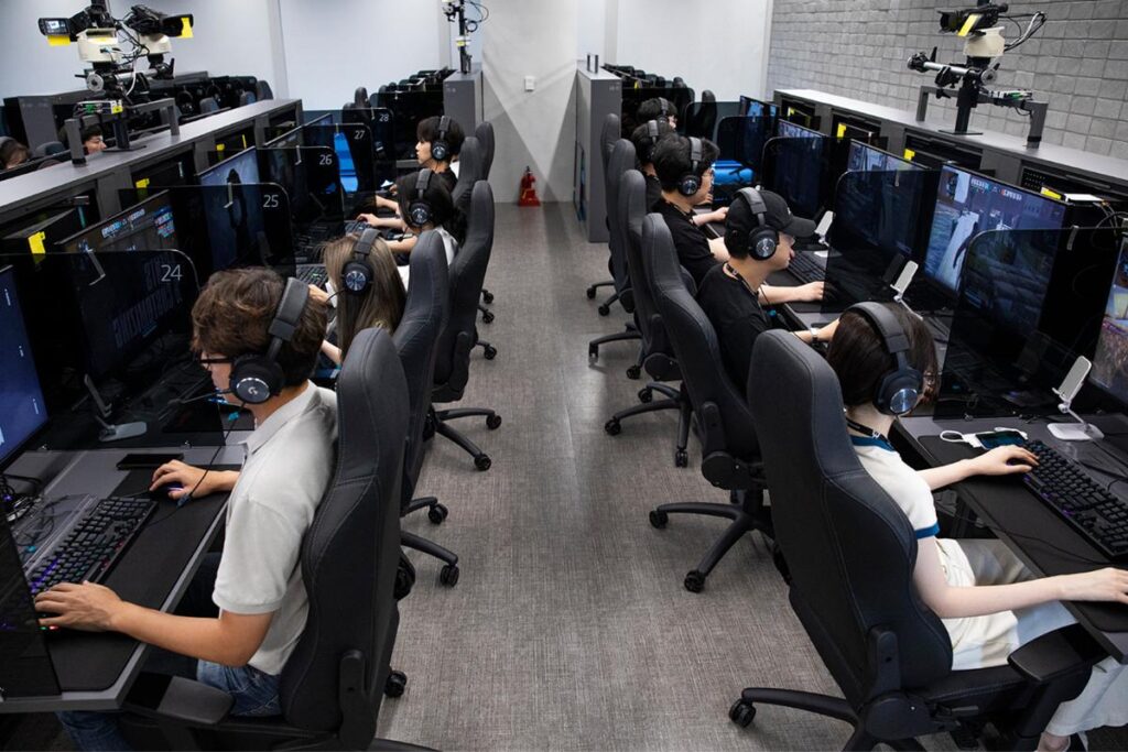 Amigos sentados lado a lado jogando dentro de um PC bang coreano