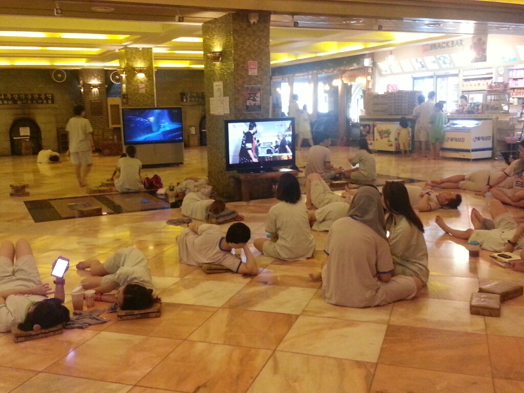 Pessoas descansando na área comum de um jjimjilbang coreano