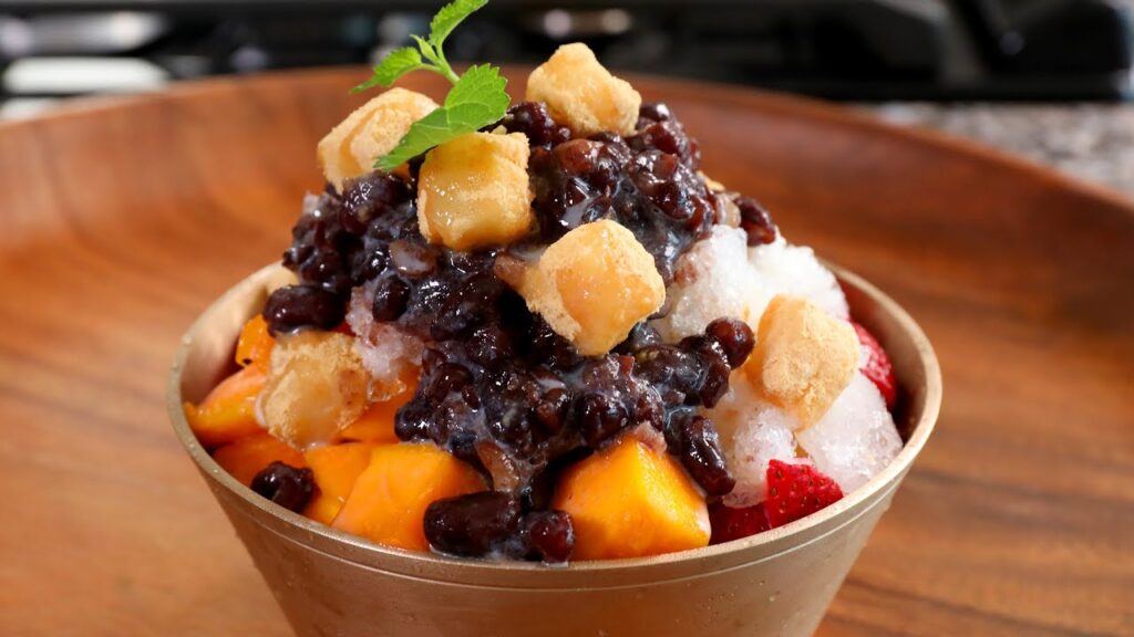 Primer plano de un bingsu coreano con fruta, judías rojas y toppings dulces