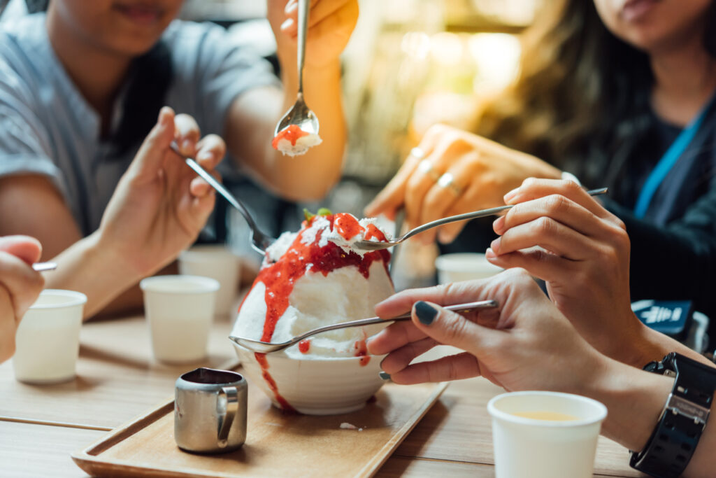 Personas compartiendo un gran bol de bingsu en una cafetería coreana