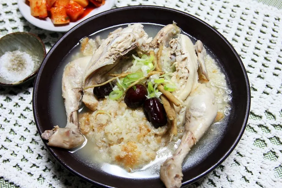 Un samgyetang abierto ligeramente para mostrar el arroz glutinoso relleno dentro del pollo.