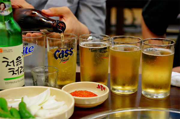 Soju e cerveja sobre uma mesa de restaurante coreano durante o jantar.