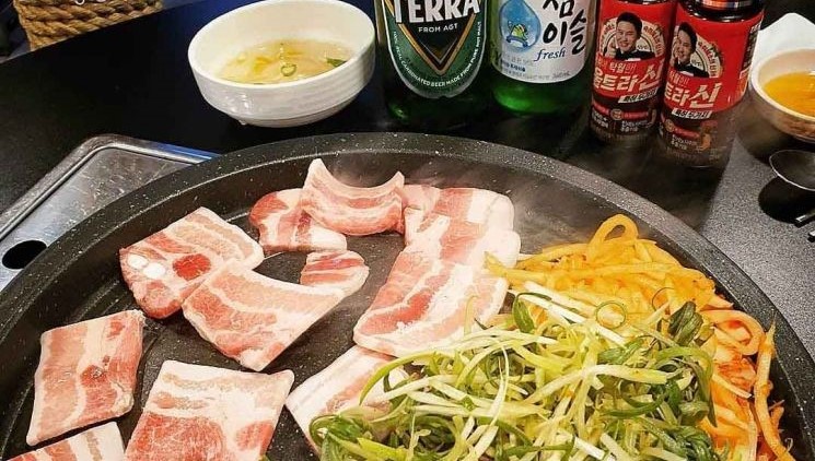 Soju e cerveja servidos junto com churrasco coreano em um restaurante.