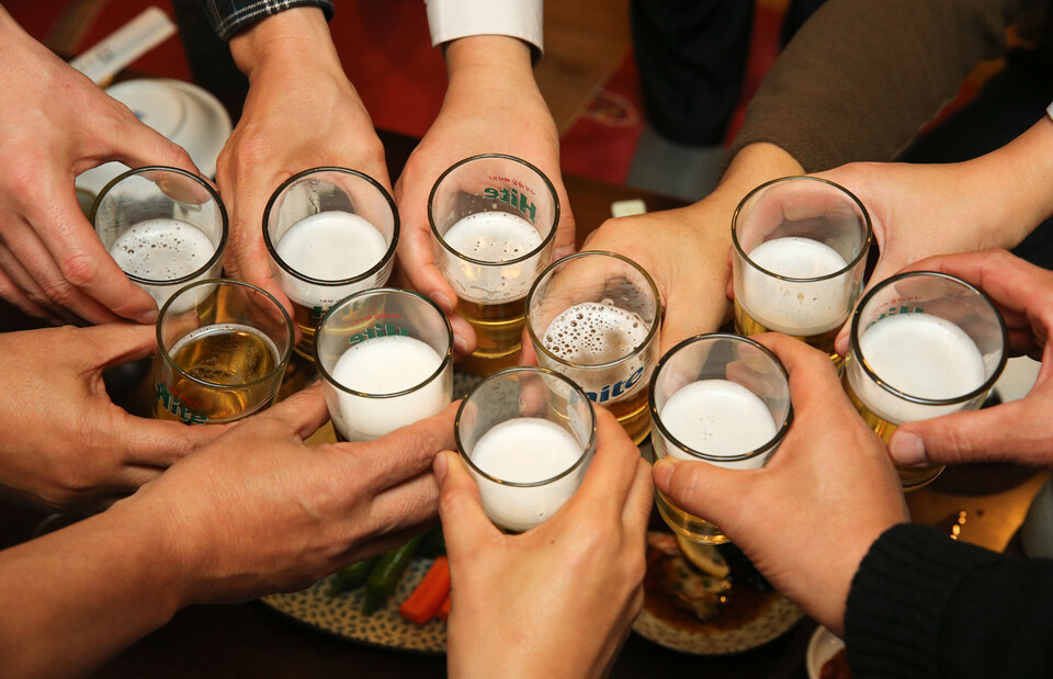 Pessoas brindando com soju e cerveja em um encontro na Coreia.