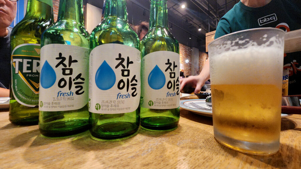 Garrafas de soju, copos de cerveja e bebidas sobre uma mesa coreana