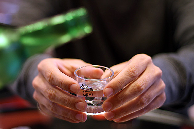 Pessoa servindo soju com as duas mãos em uma reunião coreana