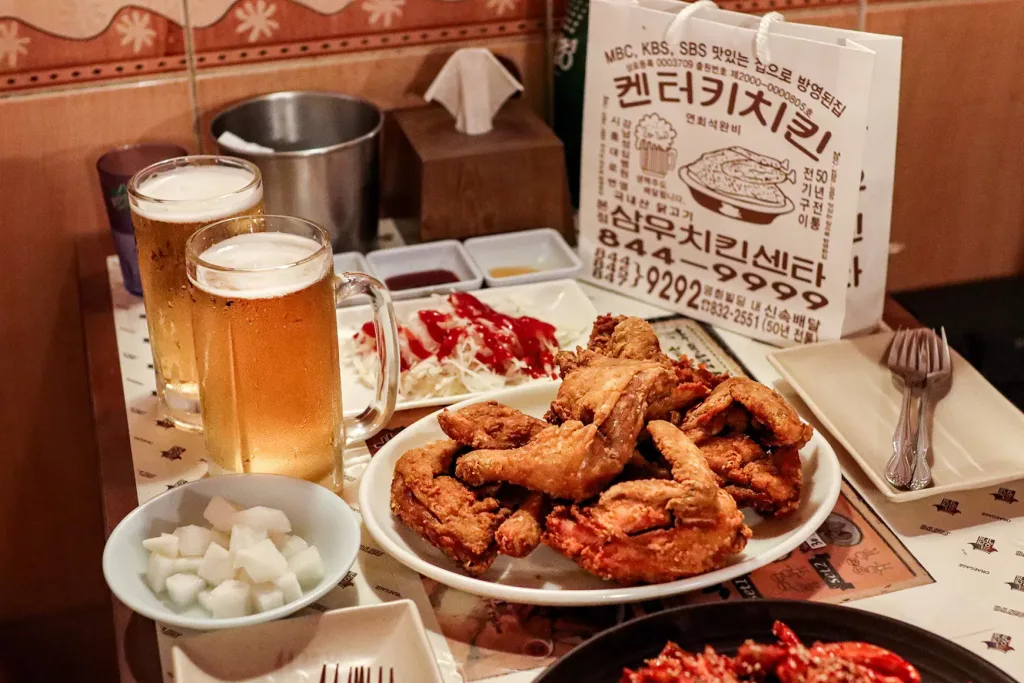 Pollo frito coreano servido en una mesa con vasos de cerveza
