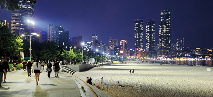 People walking along the sand and promenade at Haeundae Beach